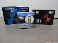 Three boxed LED headlights from different brands displayed side by side showing variety in size and branding.