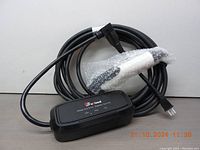 Photo showing the coiled charging cable with attached plug and portable EV charger unit wrapped partially in bubble wrap.