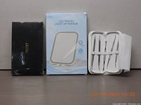 Three boxed items including black box for brush kit, blue and white box for LED mirror, and white folded case with grooming tools