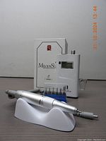 Photo showing main control unit with LCD screen, handheld drill pen and original box in background