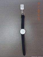 Top-down photo of a Victoria Hyde women's wristwatch laid flat, showing the small white dial and black leather strap with gold-tone buckle and original tag attached.