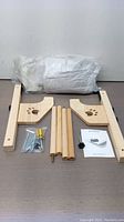 Unassembled wooden frame parts, screws, knobs, and plush cushion laid out on table