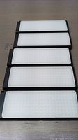 Five black-framed rectangular LED light panels laid flat with diffuser covers visible.