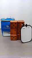 Six wooden dice stacked in 2x3 formation with Farkle scoreboard and blue Speed Armor branded carrying bag.