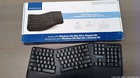 Boxed Insignia ergonomic wireless keyboard showing packaging with compatibility info for Windows OS, Mac OS and Chrome OS, and image of keyboard.