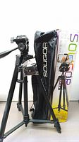 Full view of Soligor tripod assembled with quick-release plate installed, carrying case beside it, box in background showing product image and details.