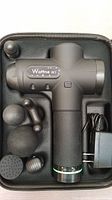 Wattne W1 massage gun and six different massage heads arranged inside custom foam cutouts within the carrying case. Charger cable placed beside the device.