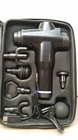 Top view of Carecj handheld massage gun with six different attachments arranged in a black zippered carrying case.