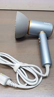 Dxliwky hair dryer with diffuser attachment laid flat showing power cord and handle.