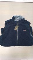 Front view of the dark navy blue heated vest showing textured fleece material and zip-up front with high collar.