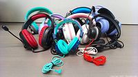 Photo showing eight mixed headphones including colorful children's styles, gaming headphones in black and red, and other wired headphones with visible microphones and cables in turquoise, red, and black.