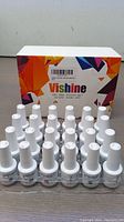 Front view of 24 Vishine gel nail polish bottles arranged in front of their colorful box with abstract design, showing white caps and clear bottles.