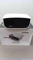 Front view of Nicpow LED projector on top of its original box showing branding and product image.