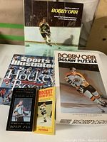 Box and some items in the lot including books and jigsaw puzzle box with Bobby Orr image.