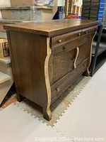 Full view of the solid wood buffet showing its curved side edges and drawer and cabinet front with original wooden knobs. Some veneer is missing from the vertical side panel.