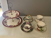 Full view of two tier ceramic cake plate with four bone china tea cups and saucers, floral patterns