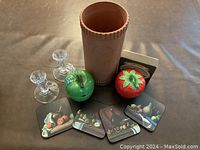 Photo showing all items of the casual dining set including the terra cotta wine cooler, two glass candlestick holders, four decorative coasters with fruit and wine images, and two ceramic jam pots shaped like an apple and a strawberry.