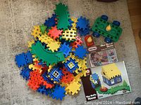 Loose colorful Little Tikes Wee Waffle interlocking plastic blocks, curved green track sections, block wheels, and character pieces, along with two Little Tikes Wee Waffle product boxes.