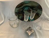 Overall view of glassware set including vase, two champagne glasses, votive candle holder, wine decanter, and decorative bowl with circular abstract design on white background