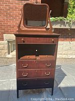 Front view of the vintage cherry veneer highboy dresser with beveled mirror placed on top.