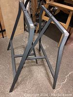 Pair of gray metal IKEA trestle table legs shown from an angle, showing rectangular frame and cross supports.