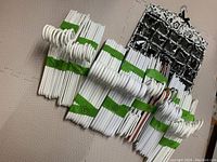 Stacked white plastic hangers bundled with green bands next to hanging jewelry organizer with black and white floral pattern and clear pockets.