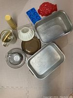 Overall view of all kitchen items including pans, moulds, measuring cups, pitcher, and glasses.