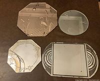 Four smaller vintage mirrors placed on floor showing different shapes and etched designs