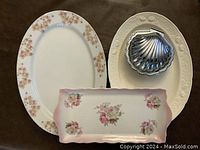 Two platters and shell-shaped butter dish arranged on surface