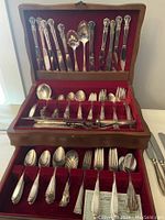 Full frontal view of the silverware chest open showing knives, forks, and spoons arranged with different handle patterns.