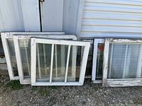 Group photo showing 5 vintage wood-framed windows leaning against a wall. One window includes vertical mullions and ribbed glass.