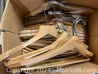 Photo showing a box with wooden clothes hangers stacked with metal hooks visible.