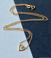 Dainty 10K gold necklace with heart pendant and diamond accent, showing chain and clasp.