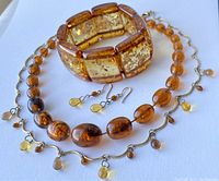 Overview showing bracelet, two necklaces, earrings with amber-coloured beads in different shapes and sizes