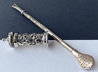 Full view of silver 925 ice tea straw and decorative container side by side on black and white background