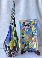Front view of Romanian rectangular art glass dish with colorful triangular motifs and tall art glass vase with blue and green twists.