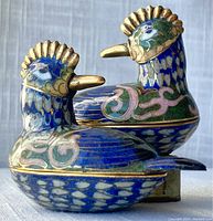 Side view of two blue bird cloisonné trinket boxes showing detailed enamel patterns and gold accents