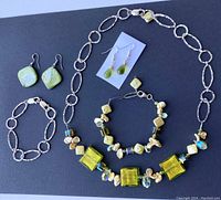 Full set on black background showing necklace, two bracelets, glasses and shell earrings