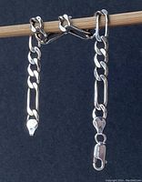 Bracelet hanging on a stick. Shows the chain links and the lobster clasp closure.
