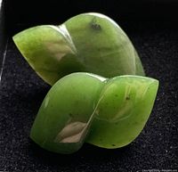 Close-up of the pair of green carved jade stud earrings with leaf shapes and natural color variances
