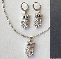 Photo showing owl pendant necklace and matching owl pierced earrings on white background