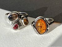 Front view of both rings showing amber and multi-gem settings