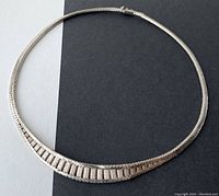 Full view of the silver choker necklace laid out flat to show the entire length and design.