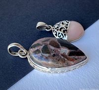 Photo showing the peach moonstone and jasper pendants on a black and white background, displaying their shape, color and silver details.