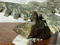 Close-up of eaglet figure beside eagle wing and base showing soapstone texture and color.