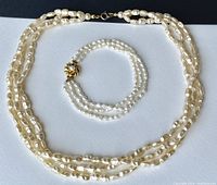 Necklace and bracelet laid flat on white surface side by side