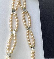 Close-up showing linked faux pearl oval loops connected by clear diamond style glass beads with silver tone settings.