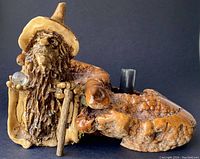 Front angle view showing the carved wizard with crystal ball and cane attached to the wood base. The wood base includes moss-like textures and the black flower holder.