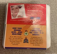 Metal tin with cover insert showing promotional message about dreams, anti-drug campaign, and local police partnership.