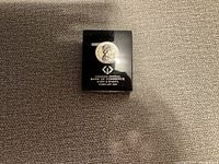 Photo of a black plastic display case containing a Canadian silver dollar coin, with inscriptions including the issuing authority and date.